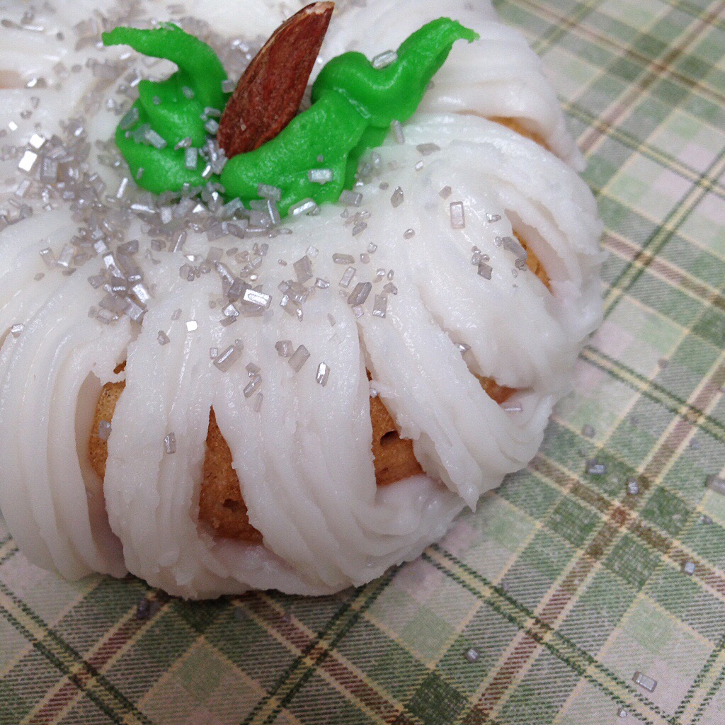 Doughnut covered in white frosting to look like a pumpkin.
