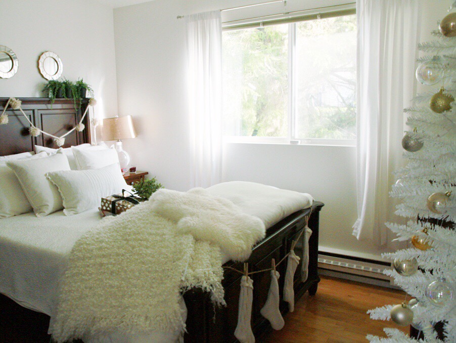 The white bedding with dark wood bed and faux fur on the bed.