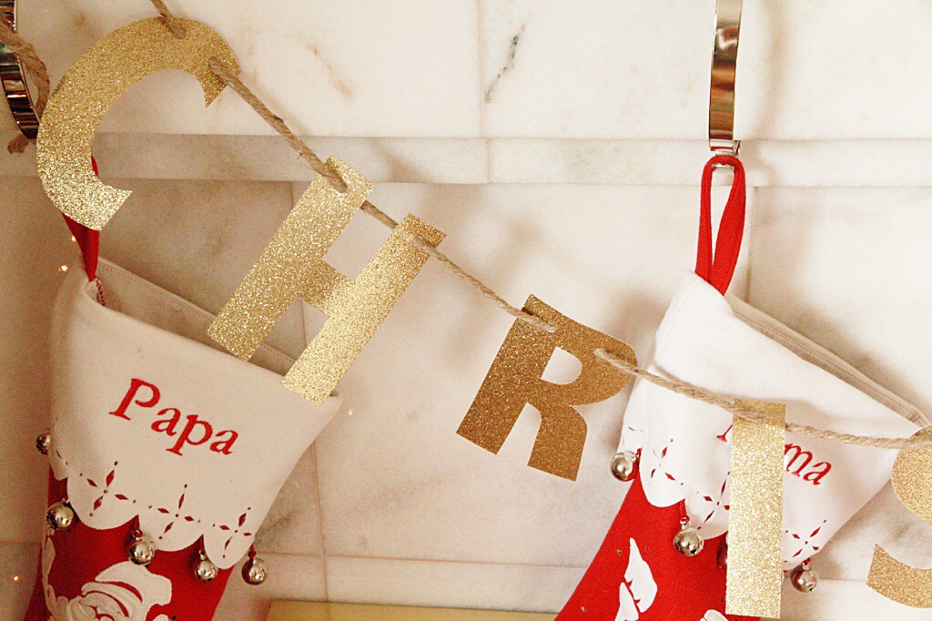 A gold Christmas banner in front of the mantel.