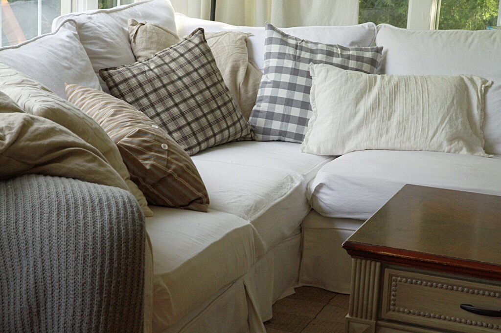 A white couch with gray and white pillows on it.