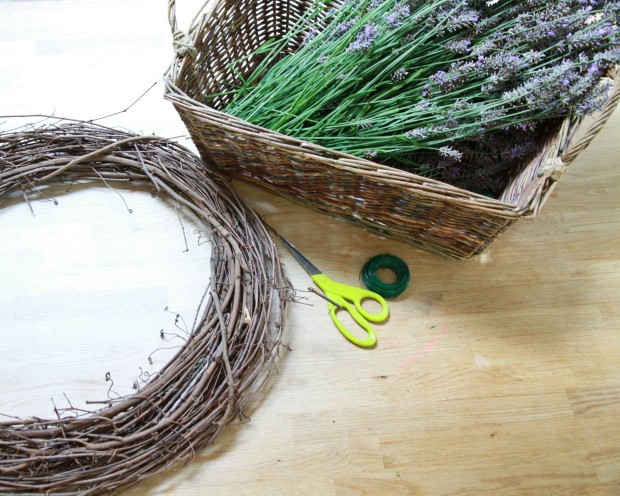 A grapevine wreath, scissors, and a basket full of fresh lavender on the counter.