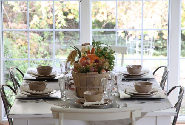 Large window with a dining room table in front of it set for Thanksgiving dinner.