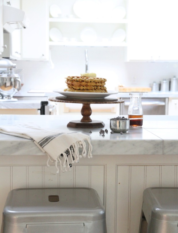 Kitchen island with silver stools beside it and waffles on the island.