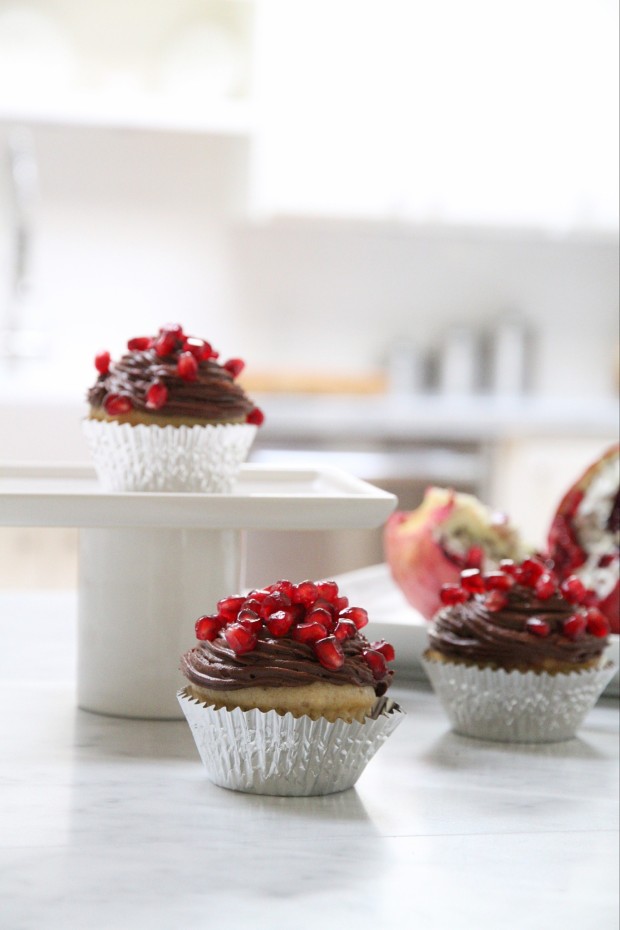 Two pomegranate muffins on the counter and one on a cake stand.