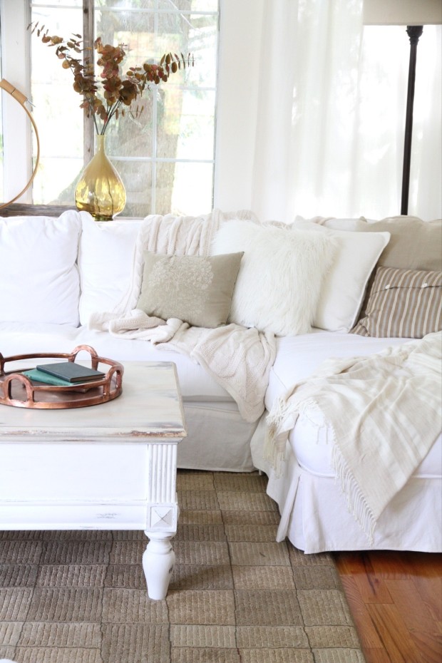 White coffee table on a cream colored rug, and a white couch.