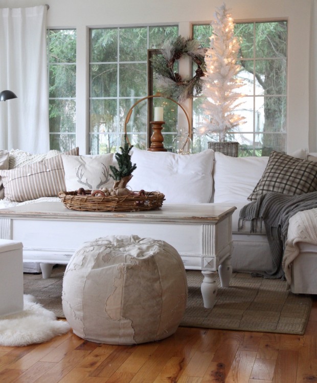 White couch, distressed white coffee table, a bean bag chair and a white Christmas tree with lights in living room.