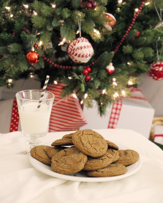 A christmas tree decorated with red and white ornaments and a plate of cookies beside it.