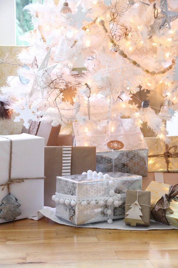 Large, small and medium presents under the white Christmas tree.
