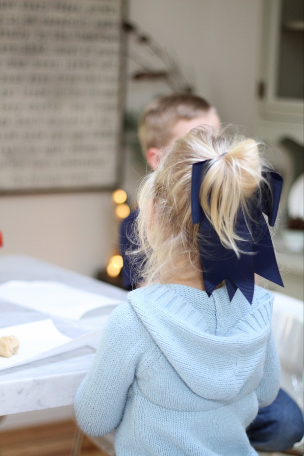 A little blonde girl at the table with a pony tail in her hair.