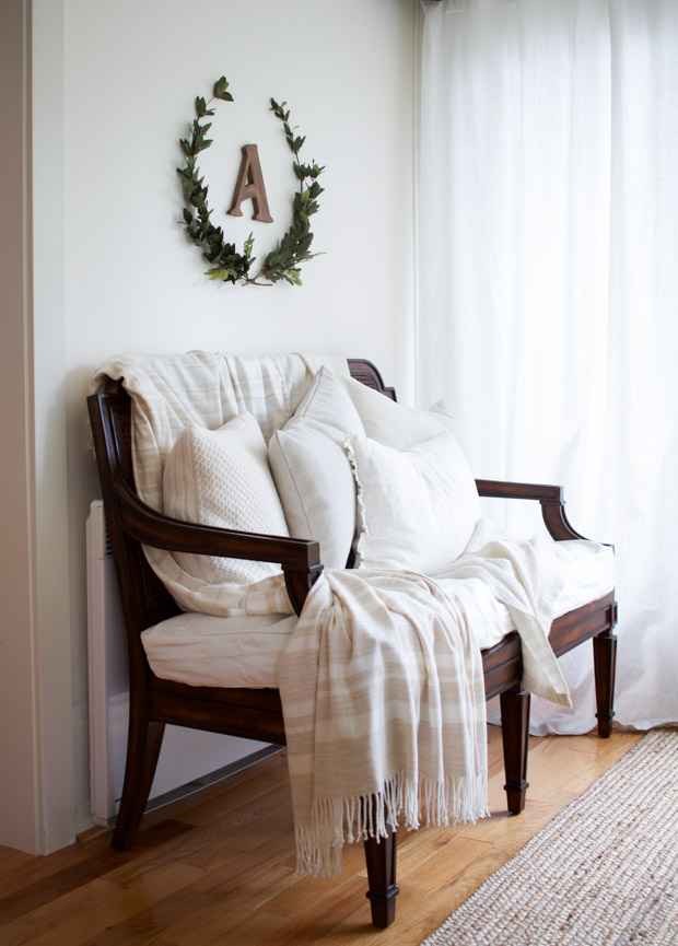 Wooden double chair, with laurel on wall above it.