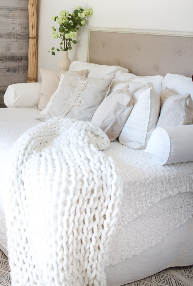 Soft neutral linen headboard with white blankets and pillows.