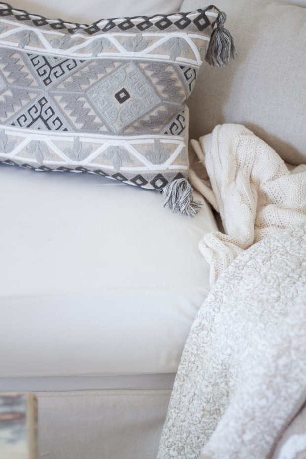 Pillow and blanket on white couch.