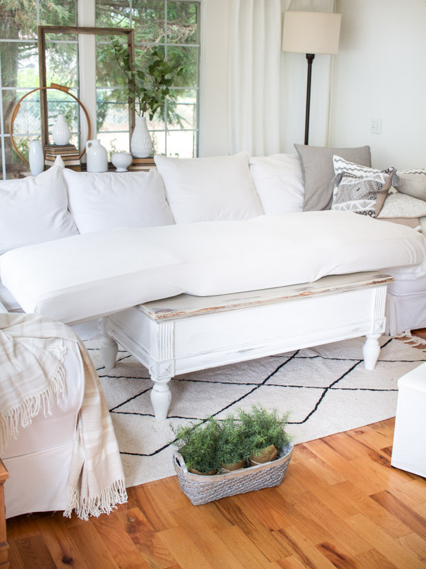 Couch in living room with white and black rug and pillows.