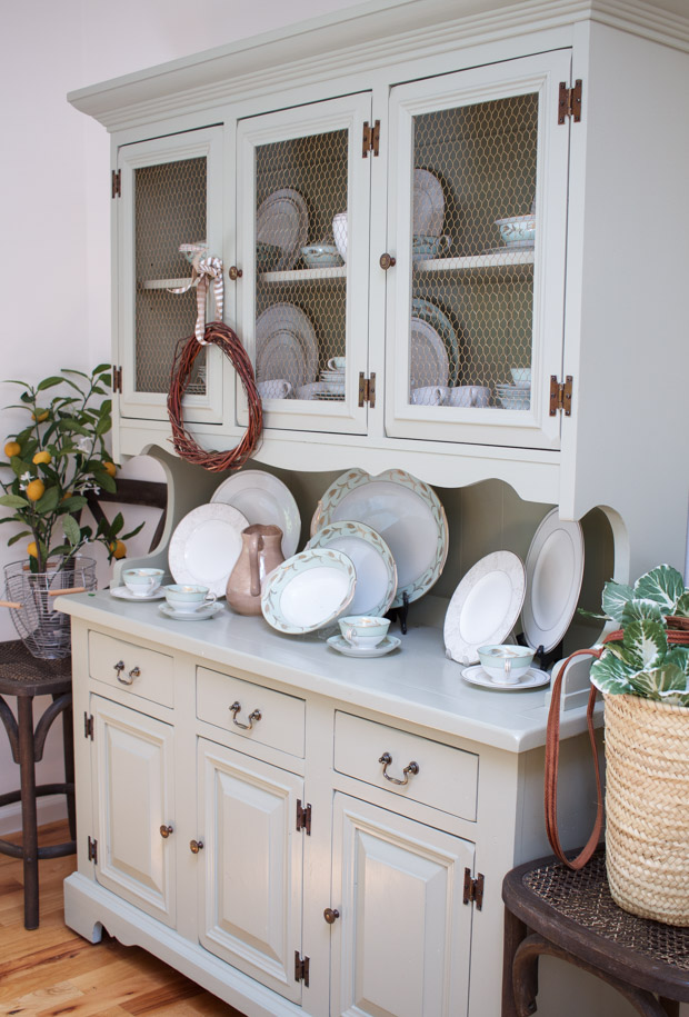 Antique bowls and cups mixed with new plates on white hutch in dining room.