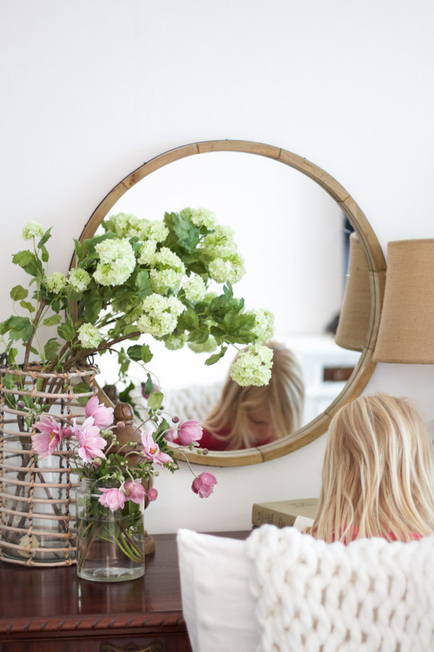 Bedroom dresser with a circle mirror above it and a little girl looking down on the dresser.