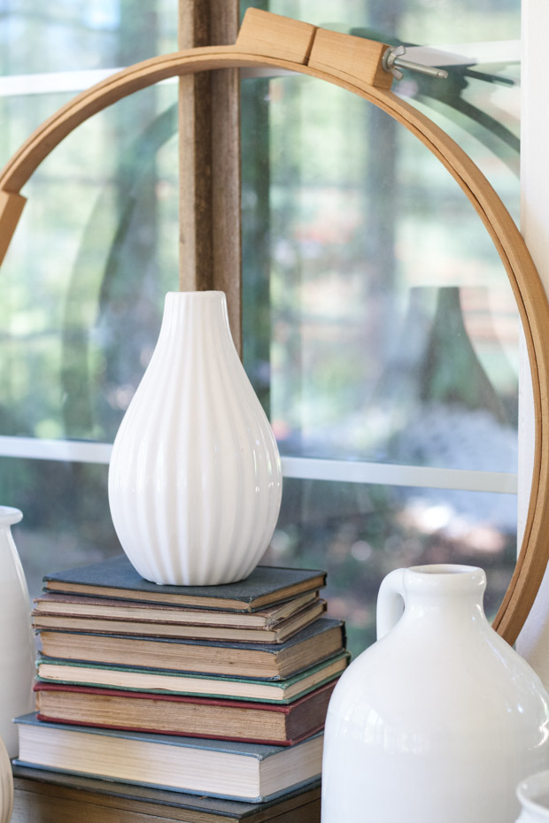 White thrift store vases on top of books on desk.