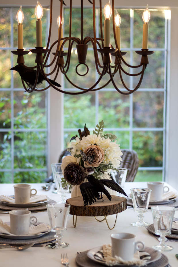 Chandelier above the table lit up with flowers on the table.