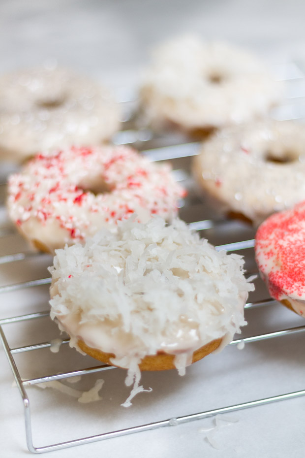 Donuts on a cooling rack with coconut and red sprinkled icing.