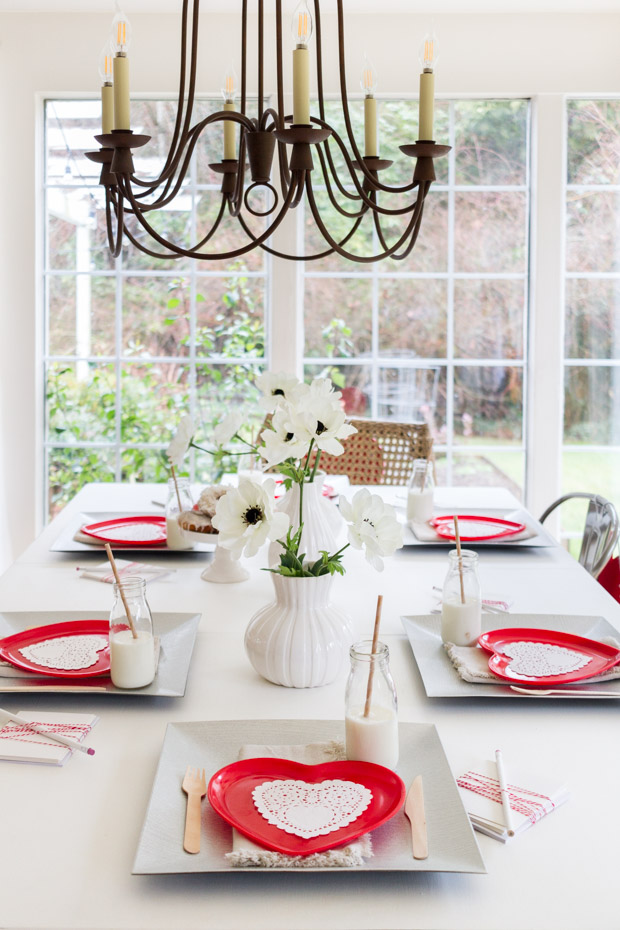 Red heart plates on the table with a metal chandelier hanging above the table.