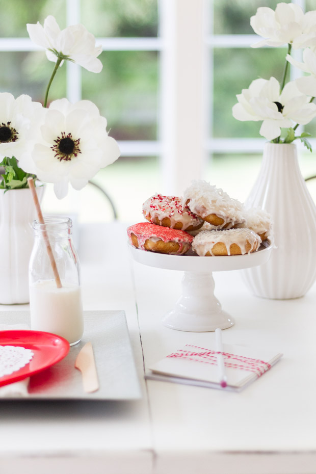 Vases filled with flowers with donuts in between the vases.