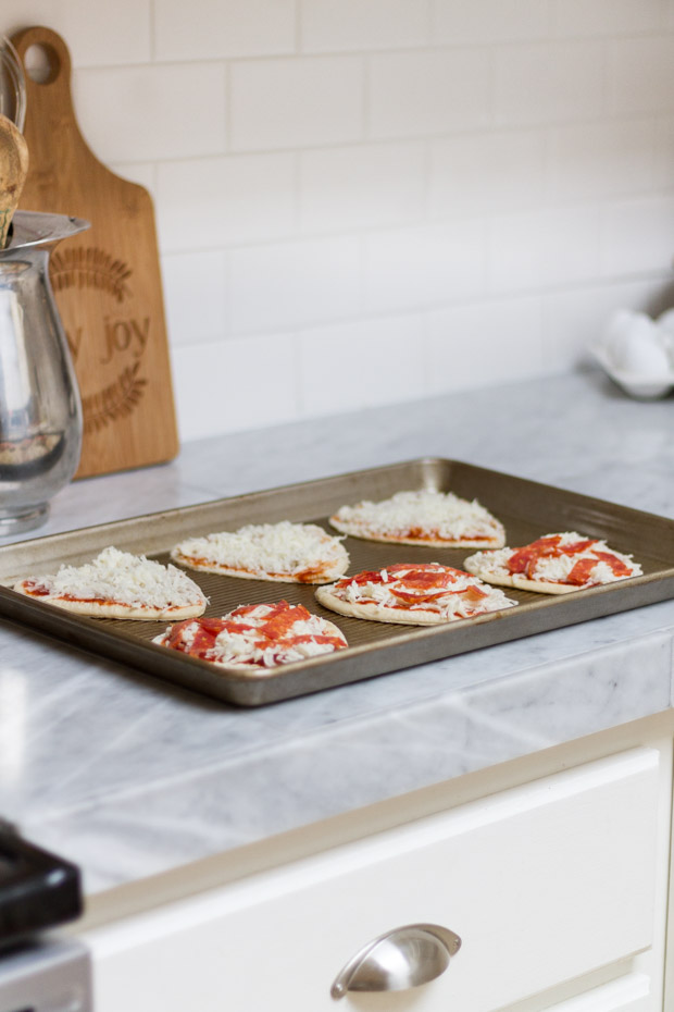 Mini heart pizzas on a baking sheet ready to go into the oven.