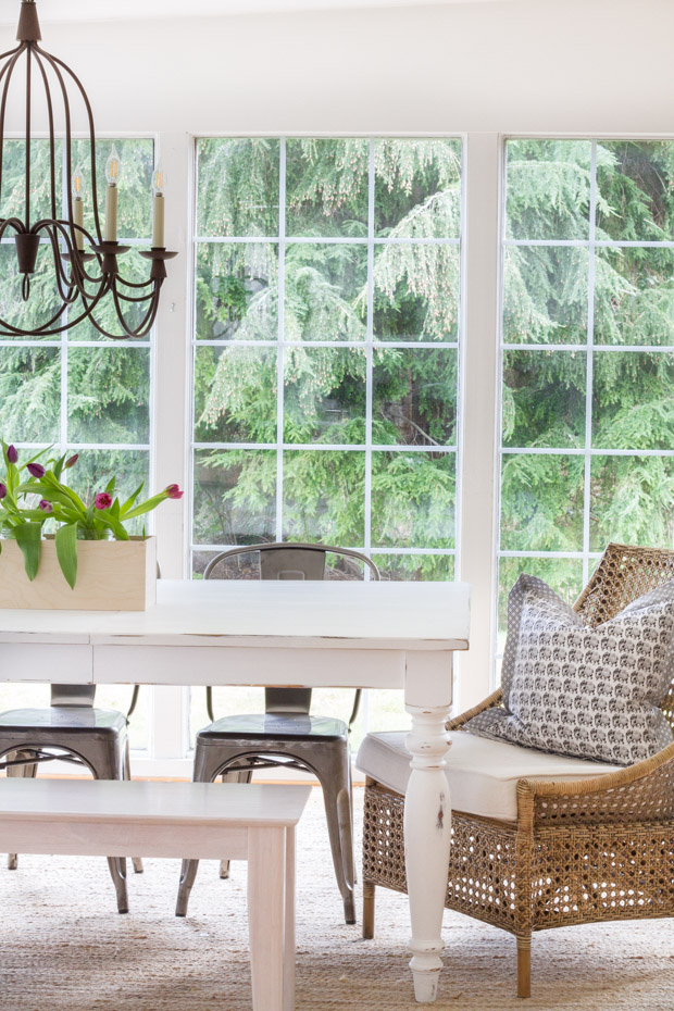 A dining room with a large window and large trees outside the window.