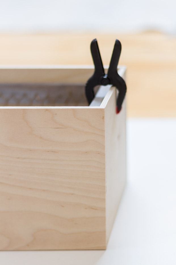 A wooden box with a clamp on the side of it.