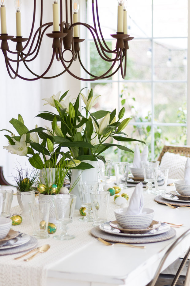 A mostly white table and table cloth, and a chandelier over the table.