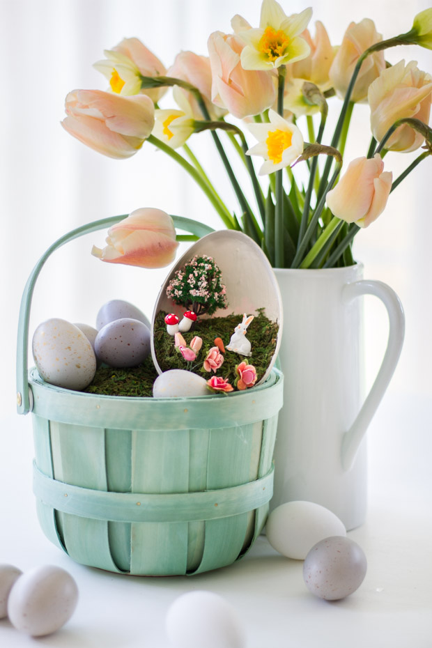 The light green decorated Easter Basket beside a white jug full of flowers.