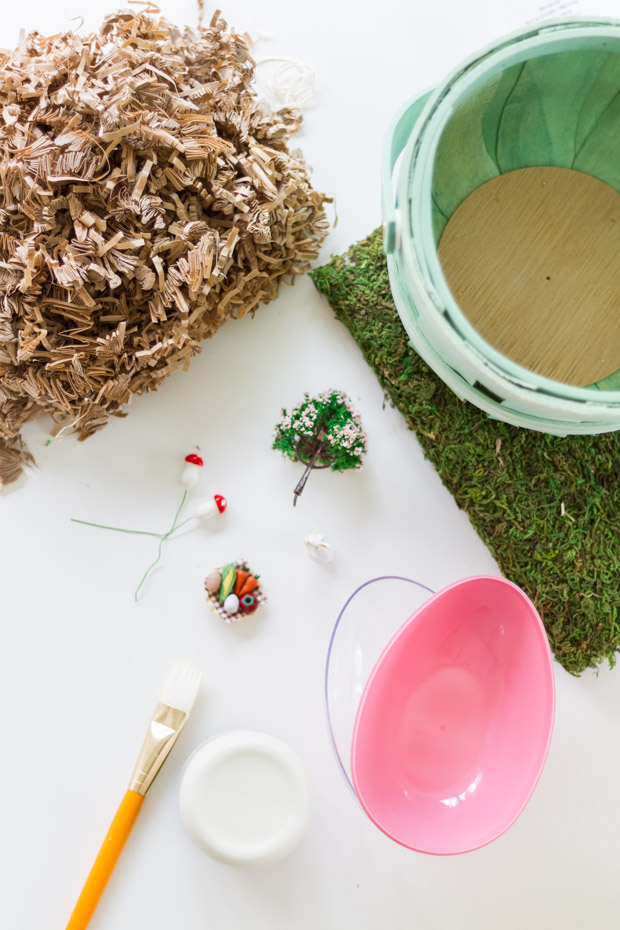 A basket, moss, a plastic egg, a brush and little ornaments on the table ready to go.