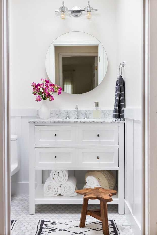 A small bathroom vanity with a wooden stool in front of it.