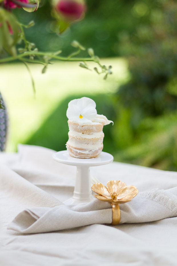 White napkin with a flower napkin holder in gold.