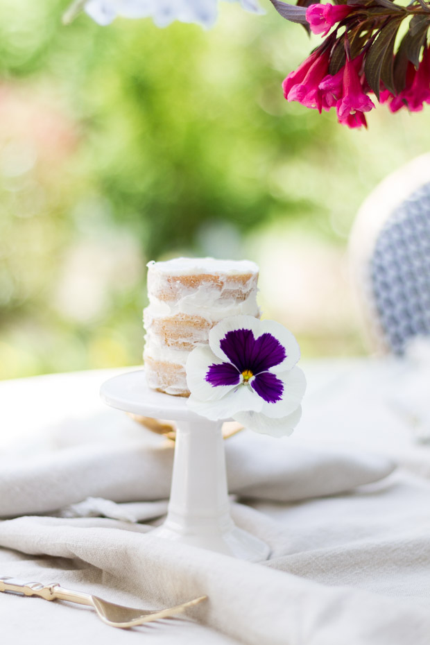 White mini cake stand with naked cake on it.