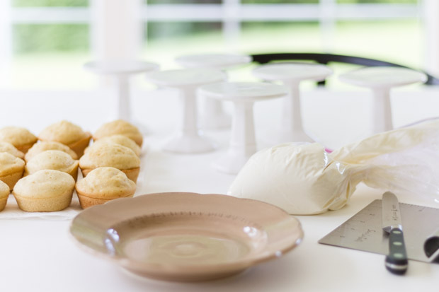 Mini cakes, a plate, and icing in a bag on the counter.