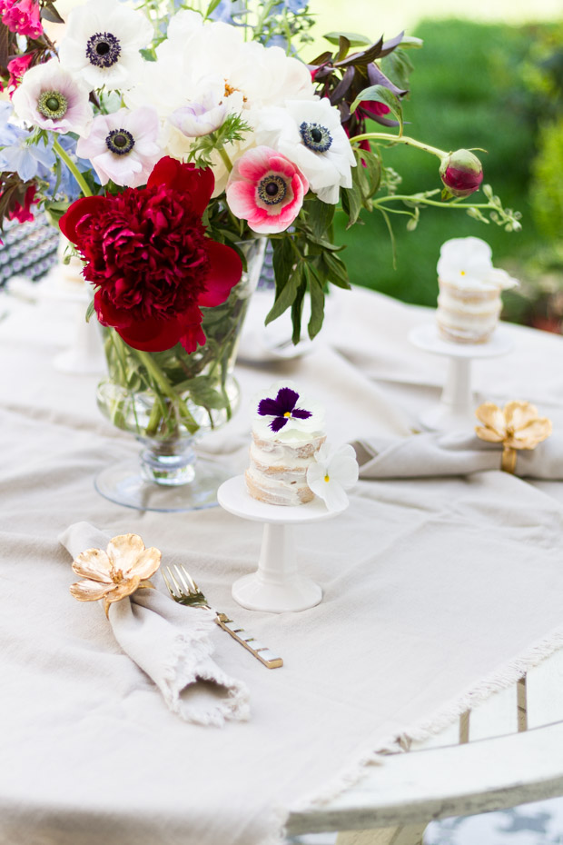 Red and white large floral bouquet in middle of white table.