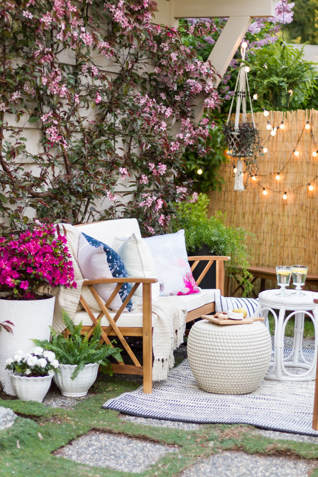 An outdoor couch, table, lights strung up.