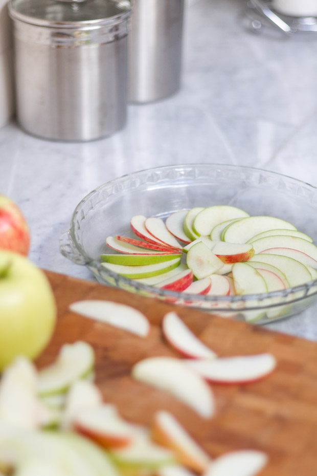 Thinly sliced apples layering in the pie dish.