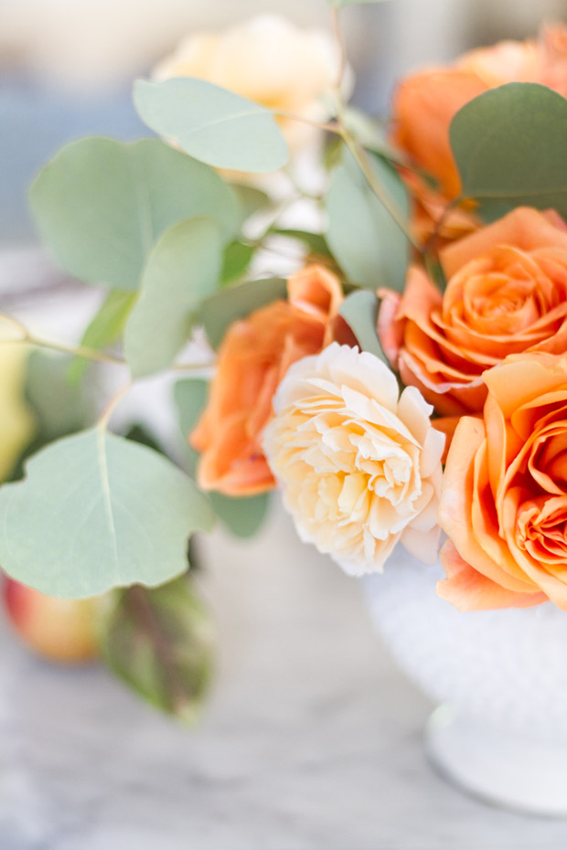 Orange and white flowers in vase on table.
