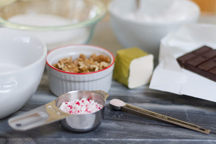 A small measuring cup with bits of peppermint inside it, and chocolate in the background.