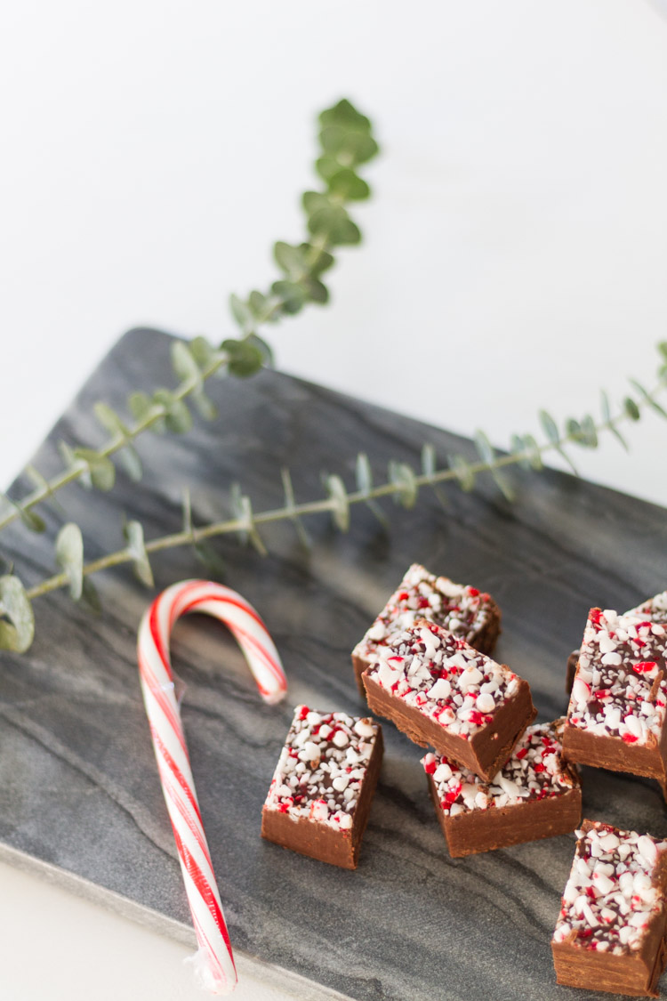 Grandma's Peppermint Fudge Recipe displayed on a marble slab with a candy cane beside it.