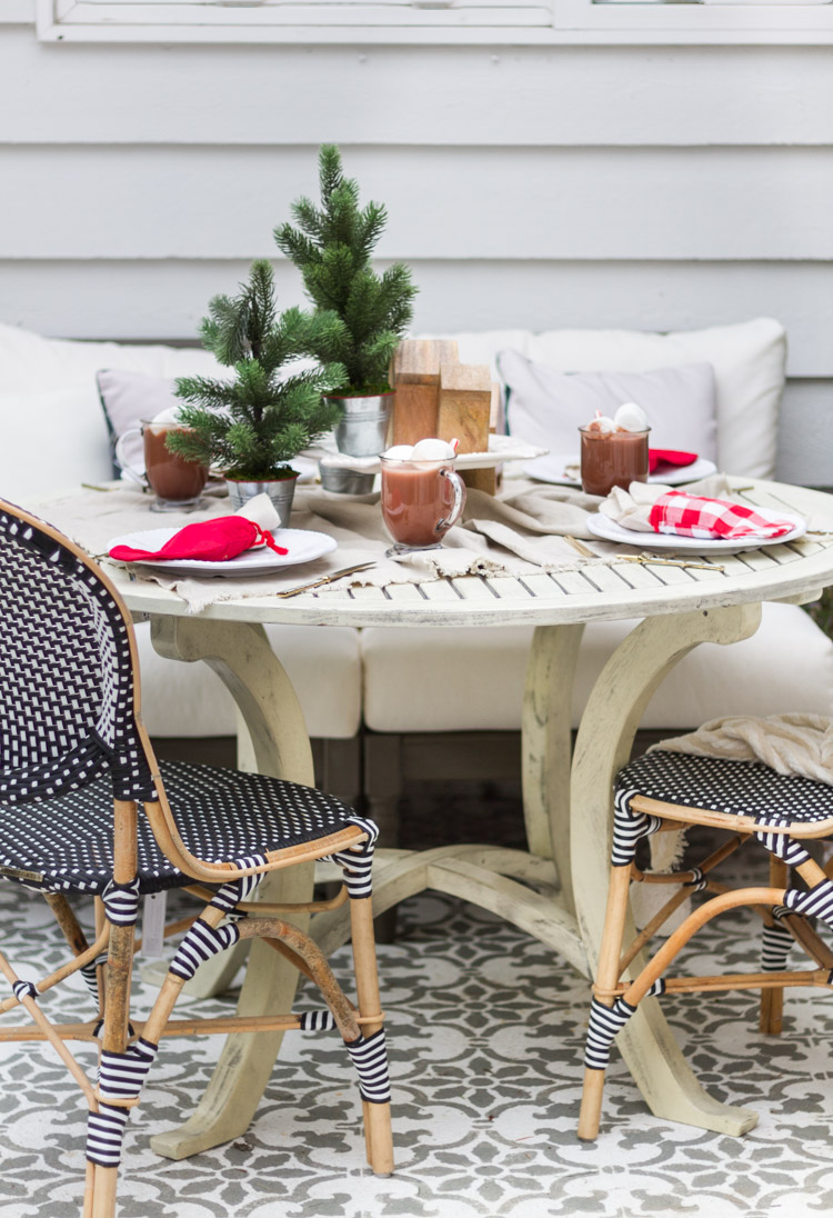 A decorated outdoor table with black and white wicker chairs surrounding it.