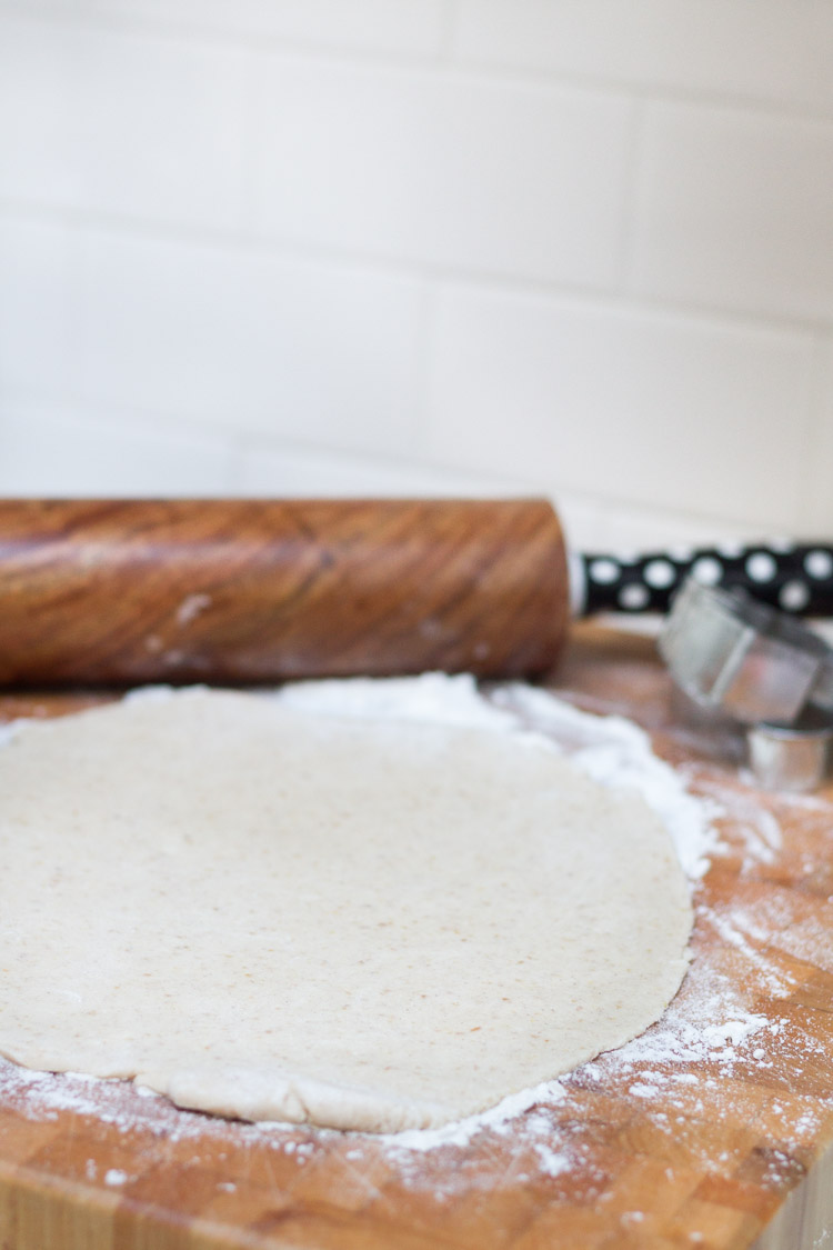 A rolling pin and the dough being rolled on the counter.