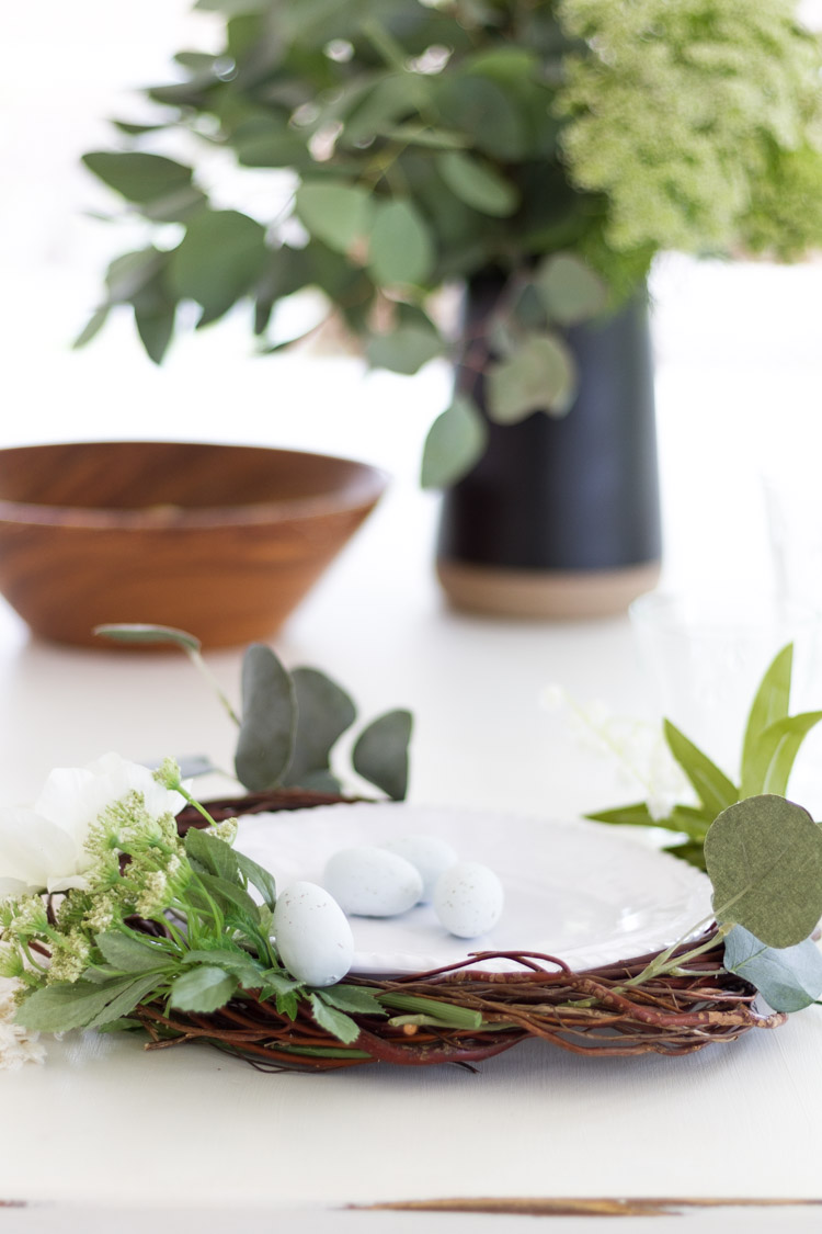 The wooden bowl on the table behind the plate on the table.