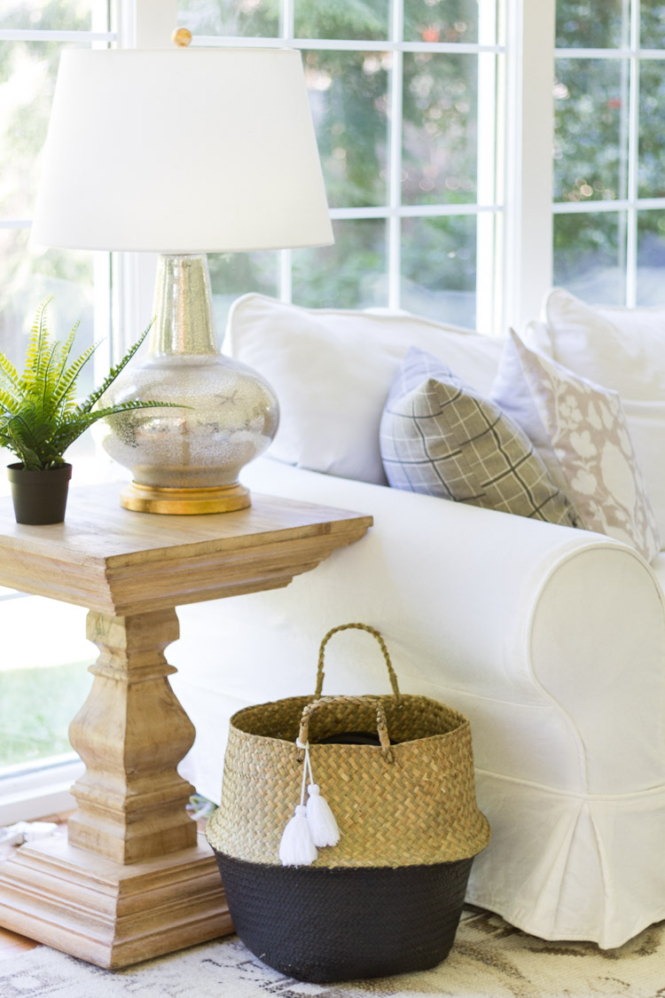 Black and straw basket beside white couch.