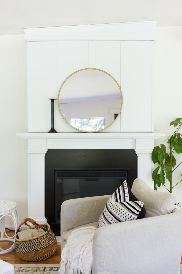 Fireplace mantel with large round mirror on it.