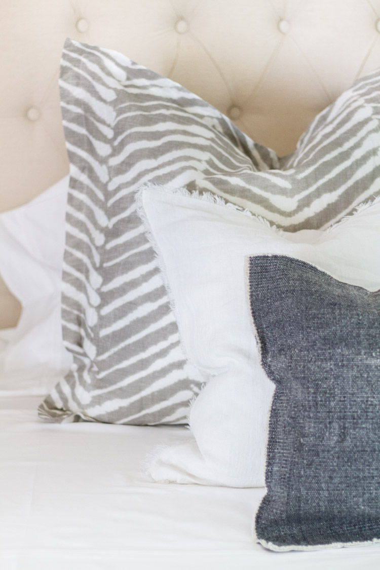 Blue, white and striped pillows on bed.