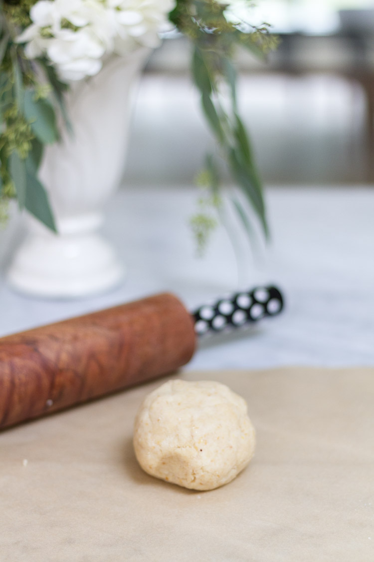 A wooden rolling pin and dough on the counter.
