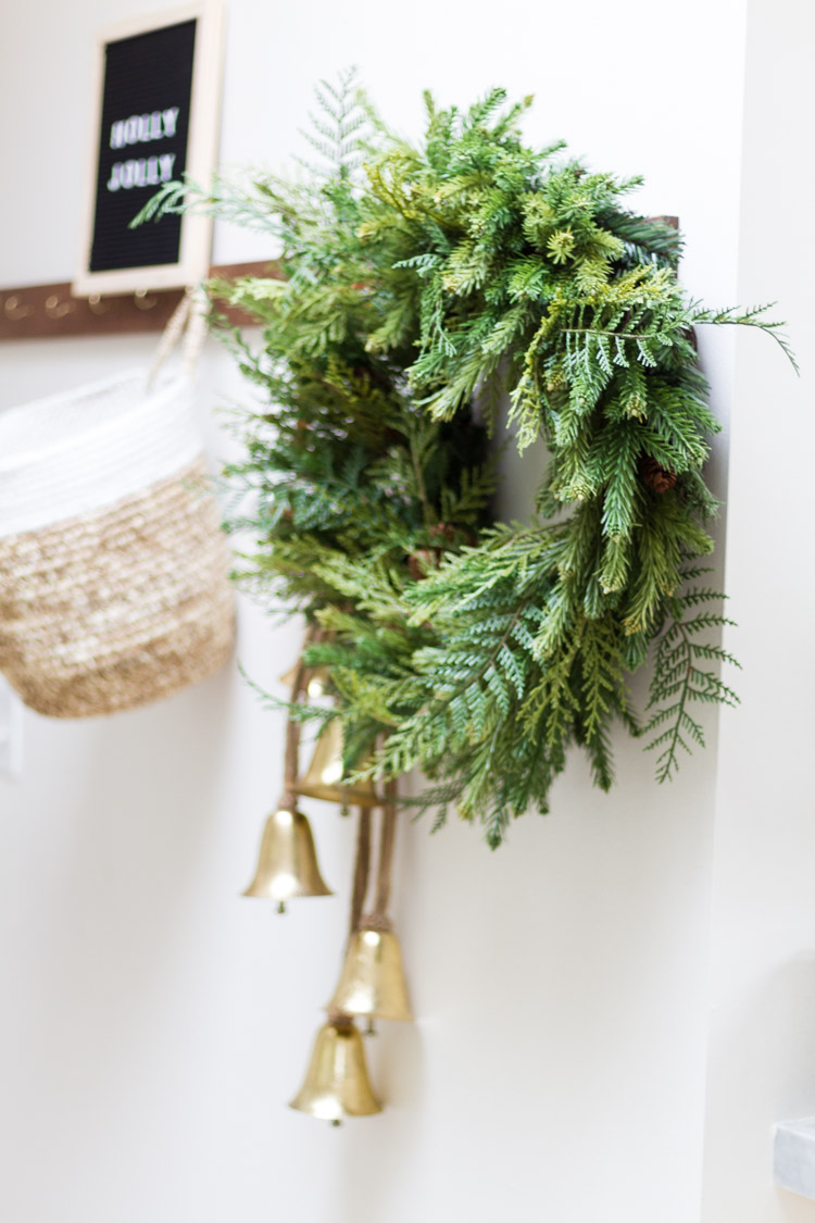 Up close picture of an evergreen wreath hanging on a coat rack.