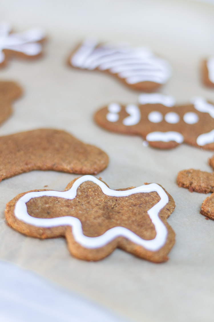 Piping white icing around the gingerbread cookie.