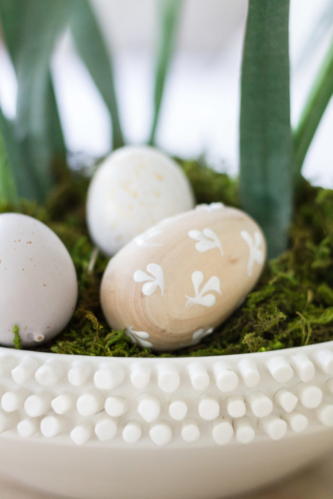 Wooden Easter eggs lying in the moss of the plant.